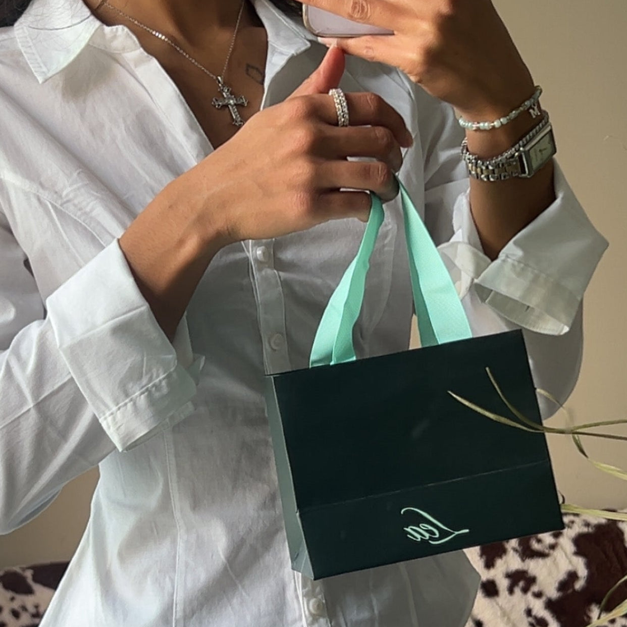 Person holding a Lea Fine Jewelry  shopping bag wearing a white shirt and jewelry from Lea Fine