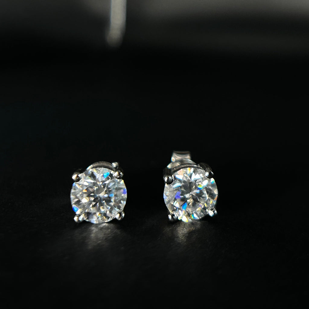 Two diamond stud earrings on a dark background