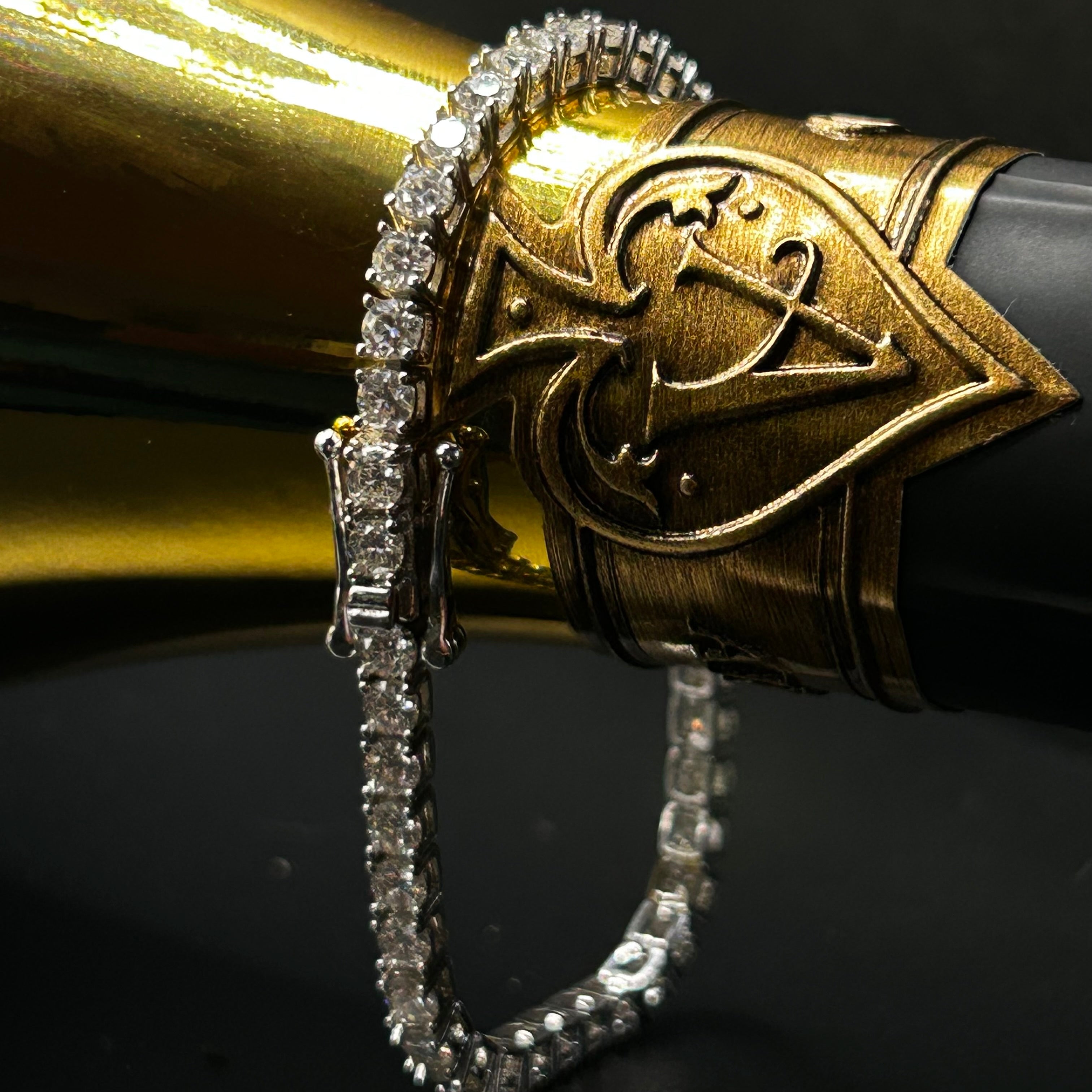 Close-up of a decorative gold and black champagne bottle with intricate design and tennis bracelet with clasp