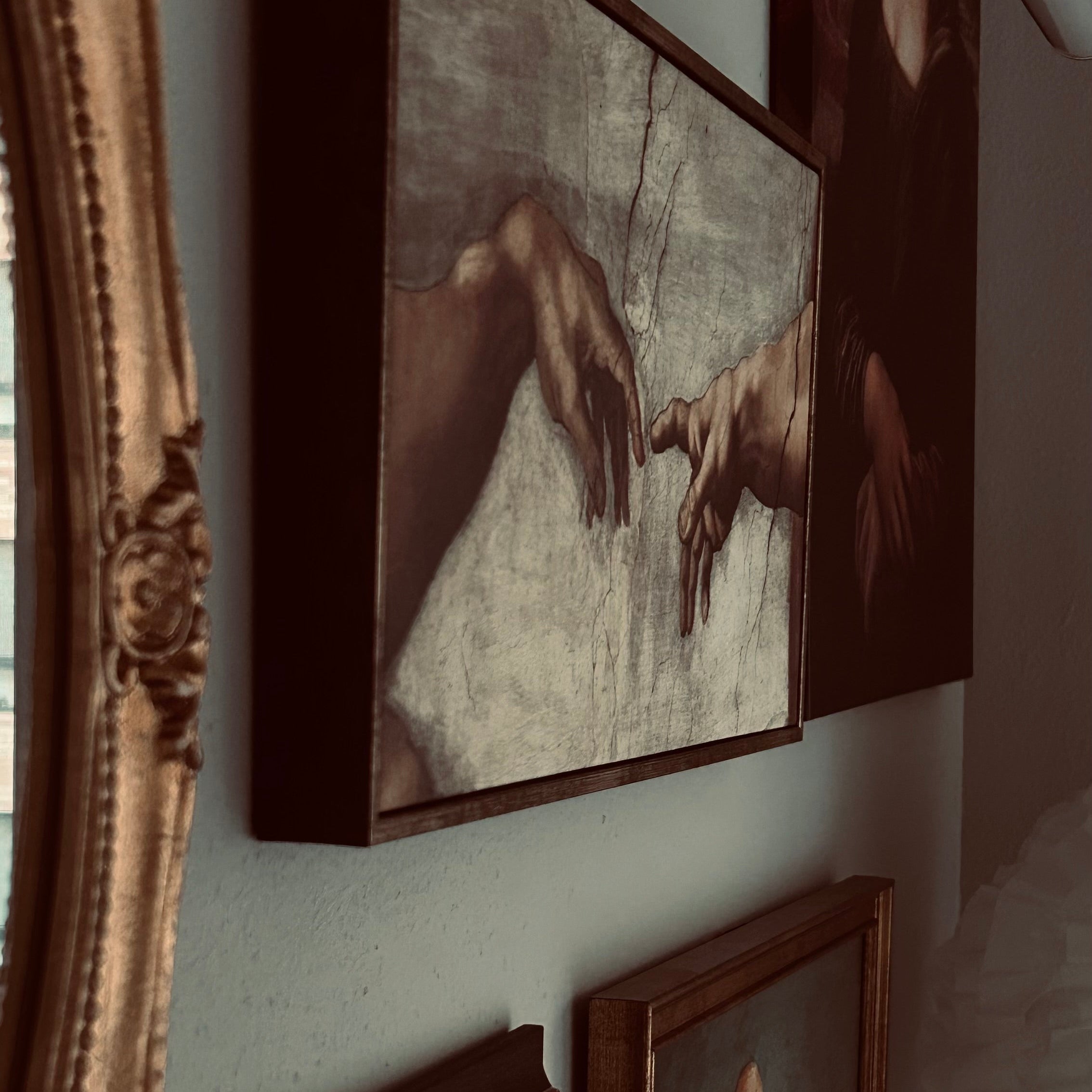 A gallery wall display featuring four framed art prints with dark brown and gold ornate frames.