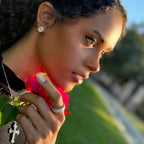 Model holding a Pink flower wearing a cross necklace and earrings from Lea Fine Jewelry
